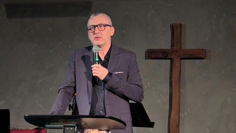 A speaker addressing the guests beside a wooden cross